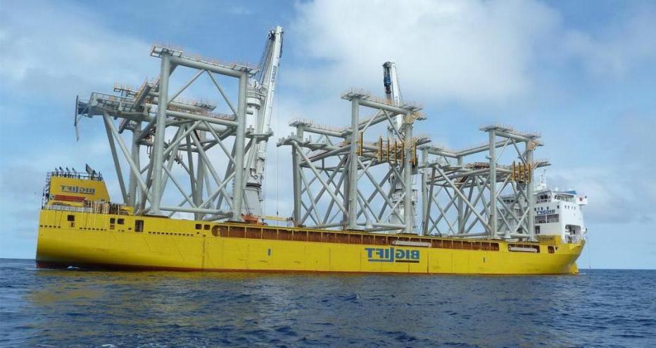 Yellow barge transporting three modules to the construction site 